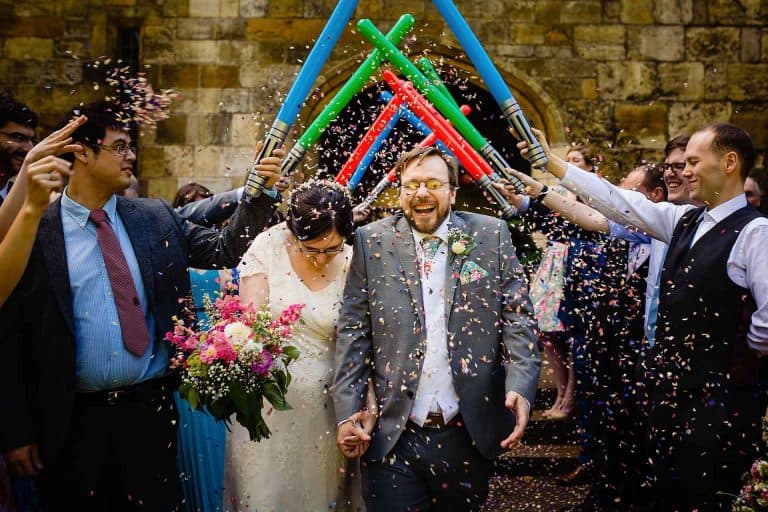bride and groom walking under lightsabers and confetti at their hospitium wedding