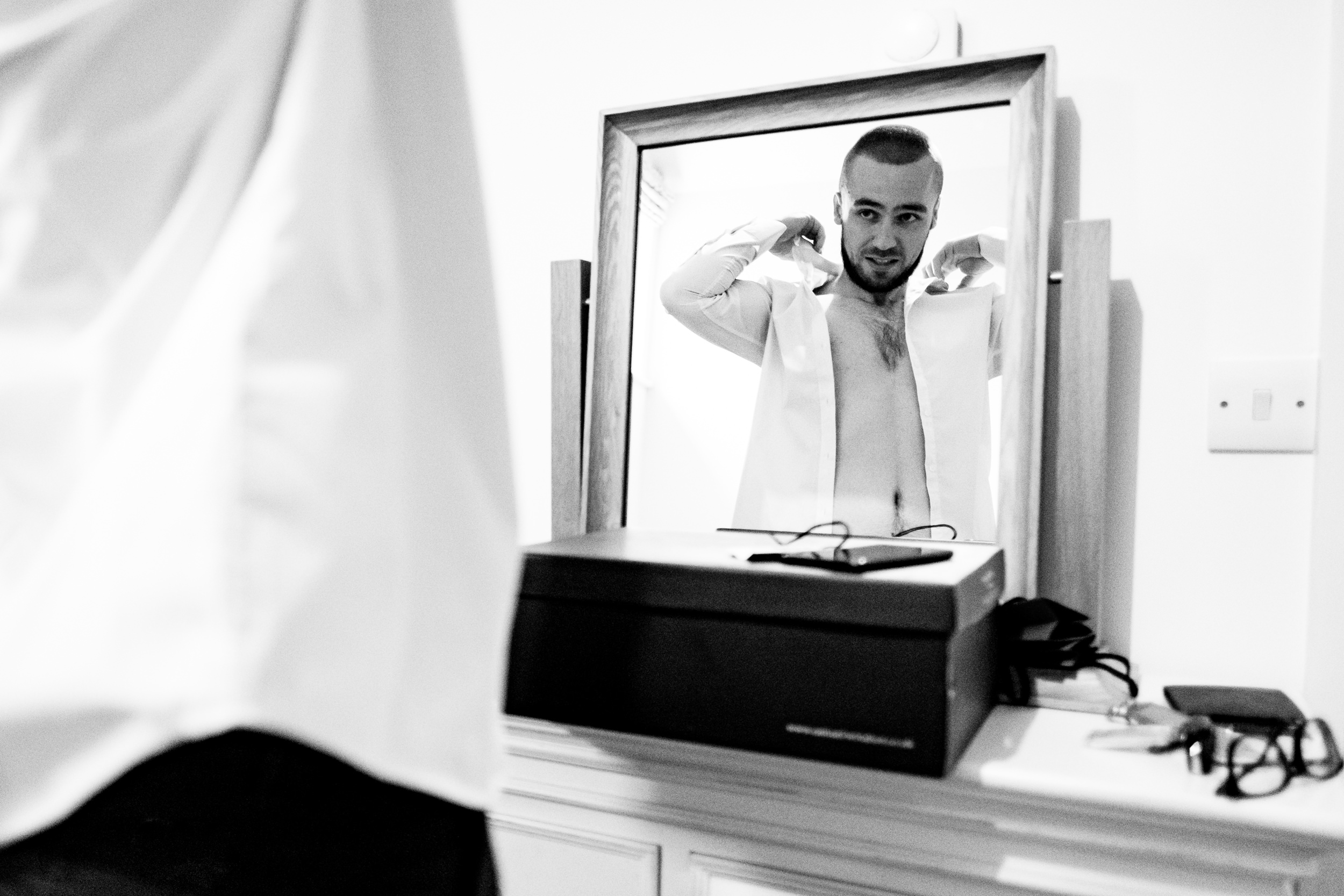 reflection of groom putting on his shirt. esk valley wedding photography by emma and rich.