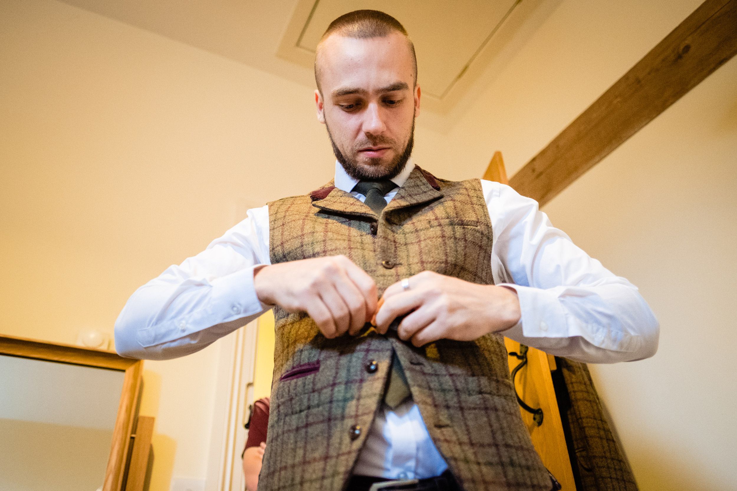 groom putting on his waistcoat. esk valley wedding photography by emma and rich.