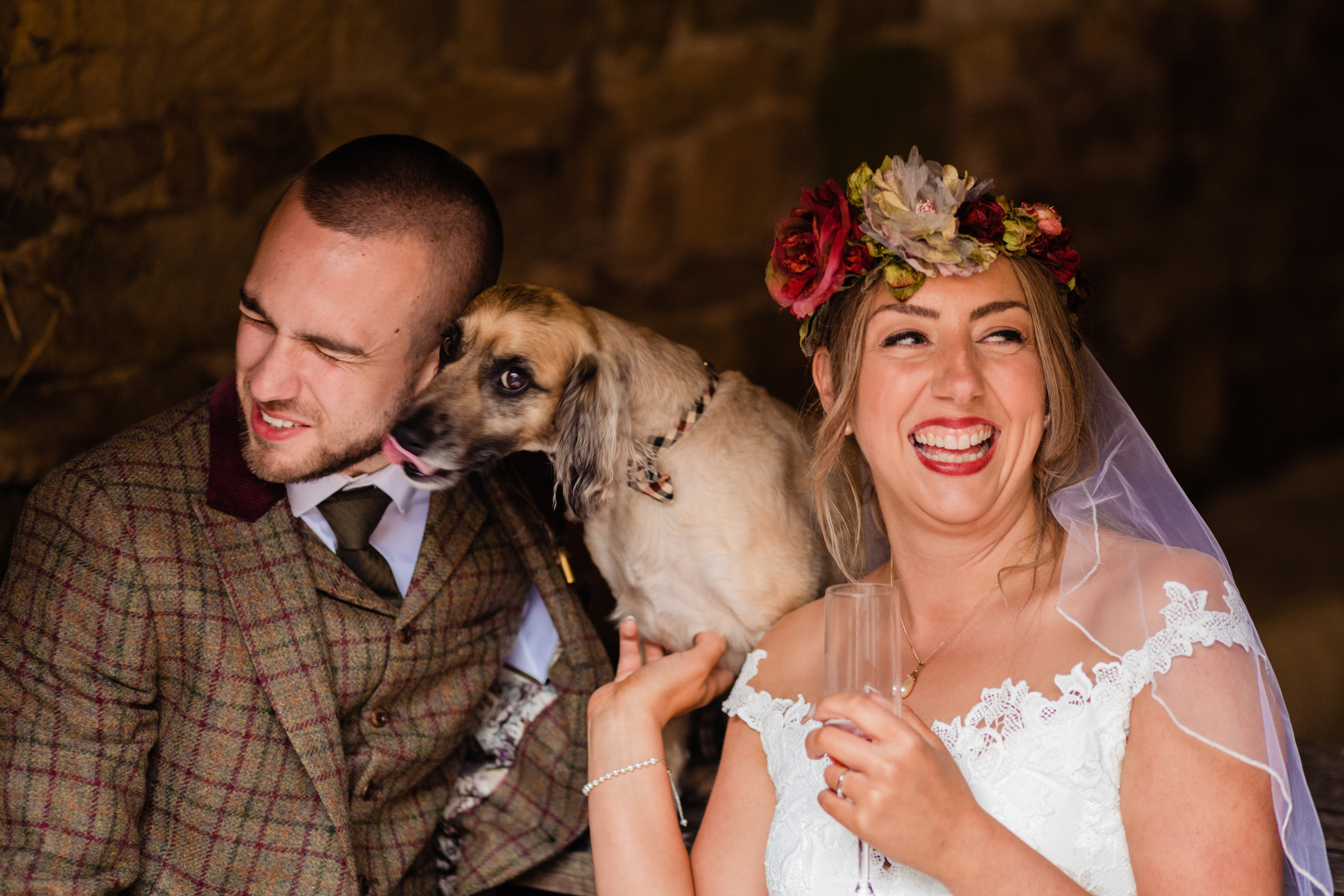 bride and groom with their dog licking the grooms face. esk valley wedding photography by emma and rich