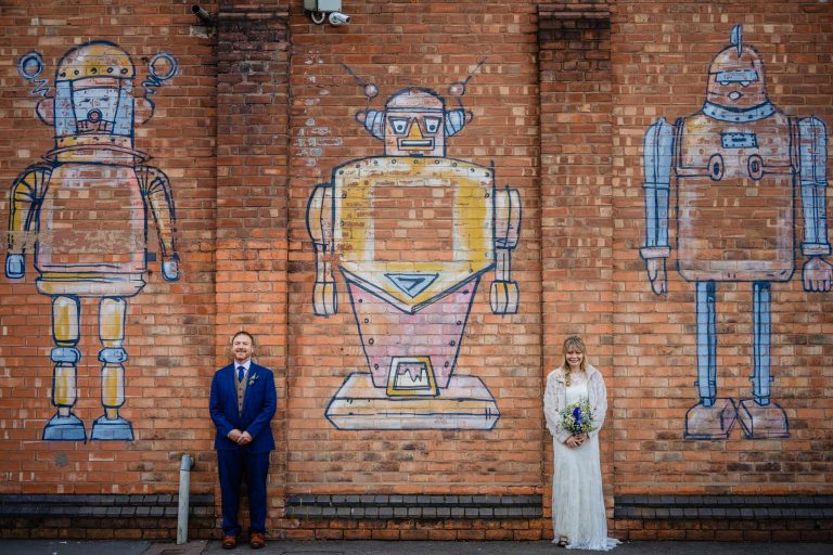 bride and groom pose for pictures in front of graffiti. birmingham wedding photography by emma and rich.