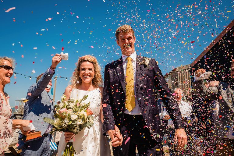 bride and groom being showered in confetti. east quay venue wedding photography by emma and rich.