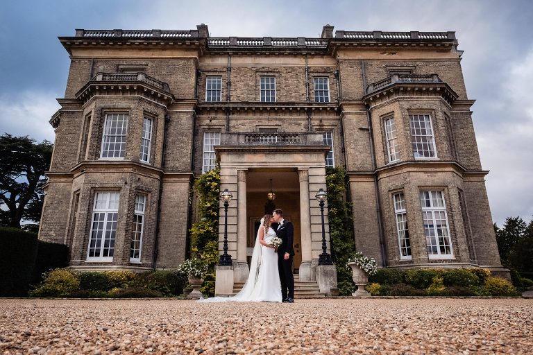 A bride and groom posing outside their wedding venue. Hedsor house wedding photography by Emma and Rich.