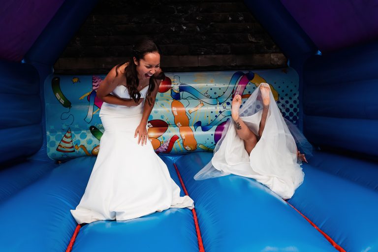 two brides jumping on a bouncy castle - rushpool hall wedding photography by emma + rich