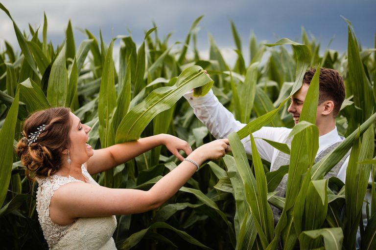 bride and groom playing with leaves in a corn field - fun and creative wedding photography by emma and rich